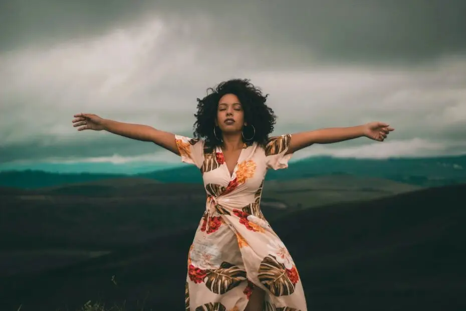 A woman standing with her arms out in font of an ocean.