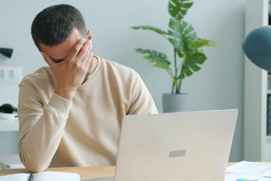 Man rubbing his face in front of laptop.